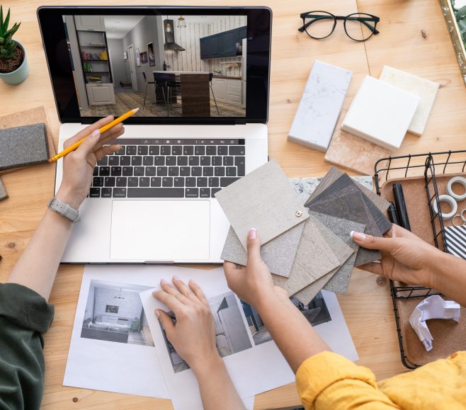 Contemporary designer pointing at home interior example on laptop display while consulting with colleague holding linoleum samples